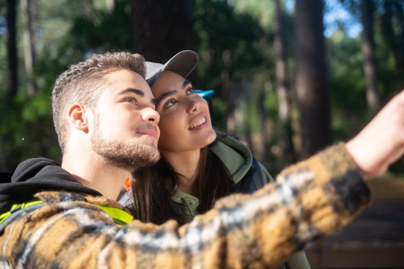 excited couple young hikers caucasian man with beard woman cap pointing looking up hobby nature love concept 1